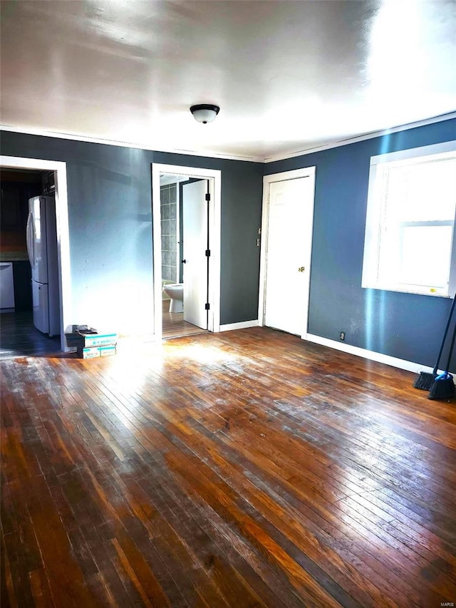 spare room featuring ornamental molding, hardwood / wood-style flooring, and baseboards