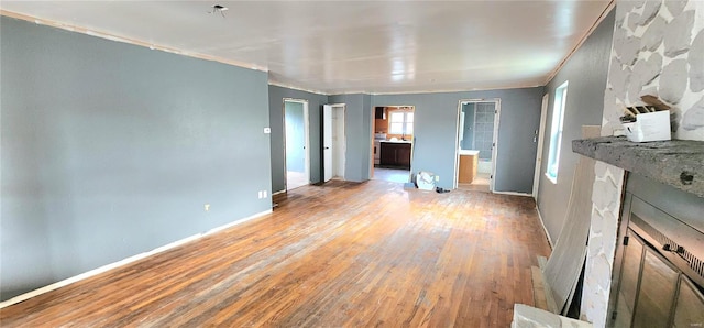 interior space featuring connected bathroom, light wood-type flooring, crown molding, and baseboards