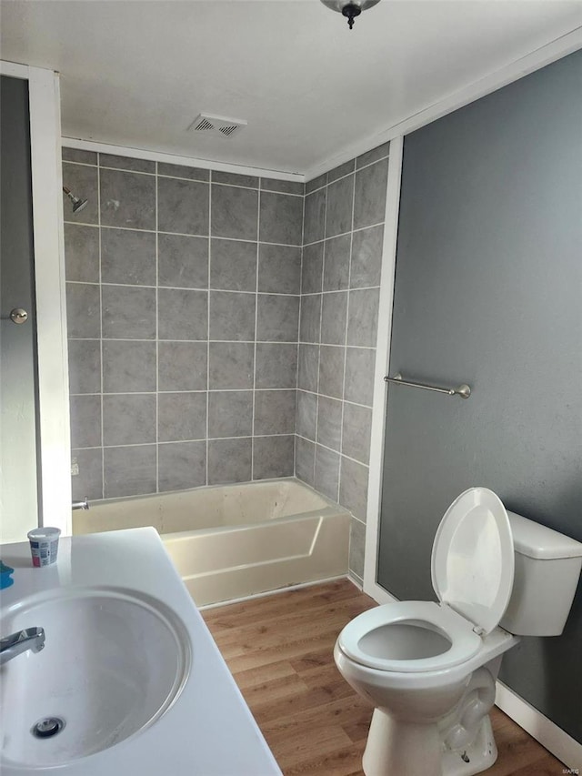 full bathroom featuring a sink, visible vents, wood finished floors, and toilet