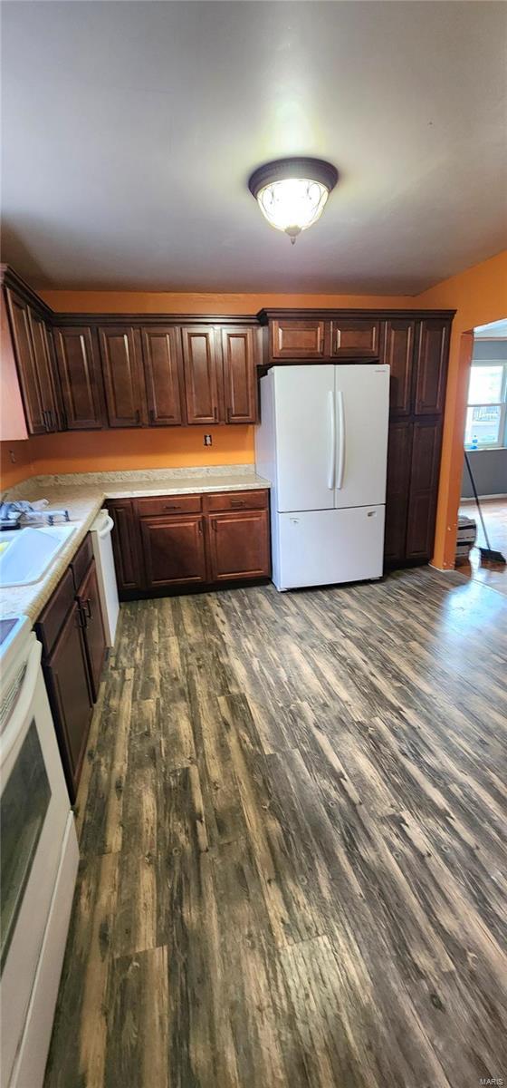 kitchen featuring stove, light countertops, a sink, and freestanding refrigerator