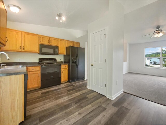 kitchen with ceiling fan, black appliances, dark carpet, vaulted ceiling, and sink