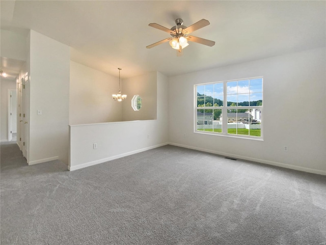 empty room featuring ceiling fan with notable chandelier and carpet floors