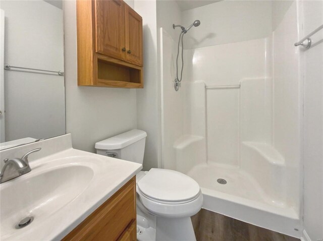 bathroom featuring a shower, hardwood / wood-style flooring, vanity, and toilet