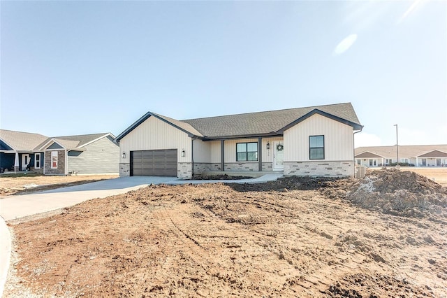 modern farmhouse featuring stone siding, driveway, and an attached garage