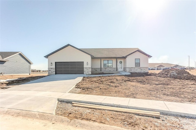 view of front of home featuring concrete driveway, brick siding, an attached garage, and stone siding