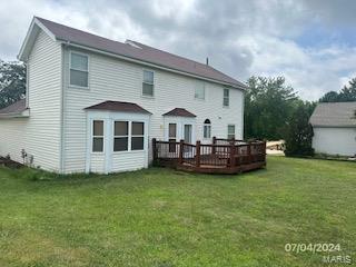 back of property featuring a deck and a lawn