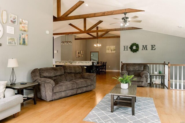 living room with lofted ceiling with beams, ceiling fan with notable chandelier, and light hardwood / wood-style floors