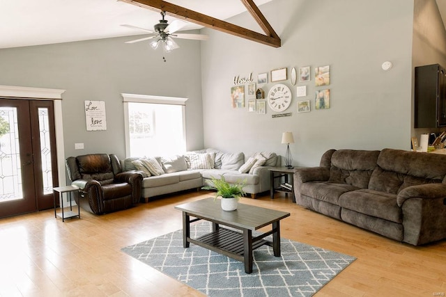 living room featuring ceiling fan, high vaulted ceiling, beamed ceiling, and light wood-style floors