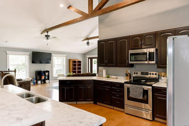 kitchen featuring vaulted ceiling with beams, stainless steel appliances, a sink, open floor plan, and light countertops