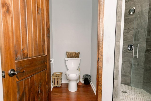 bathroom featuring toilet, baseboards, and tiled shower