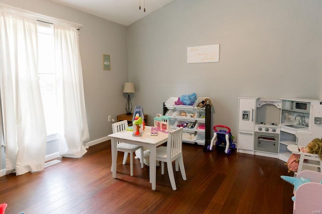 recreation room featuring baseboards, dark wood finished floors, and a sink