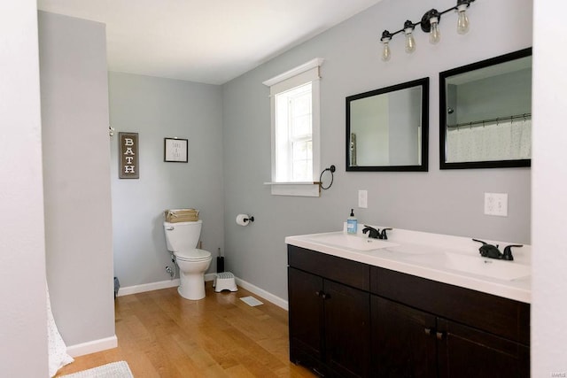 bathroom with double vanity, hardwood / wood-style floors, and toilet