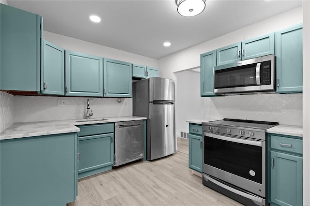 kitchen with tasteful backsplash, sink, stainless steel appliances, and light hardwood / wood-style floors