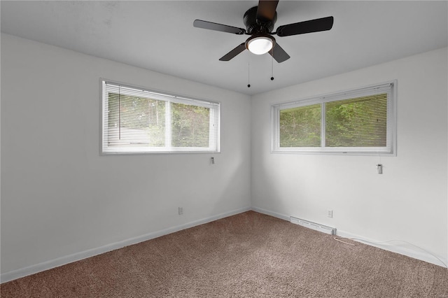 carpeted empty room featuring ceiling fan and a baseboard heating unit