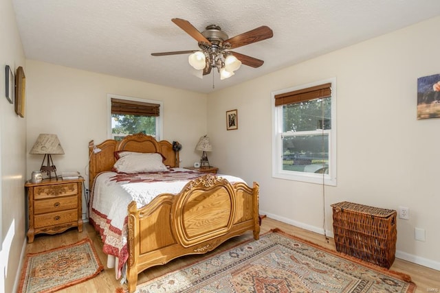 bedroom featuring ceiling fan, light hardwood / wood-style flooring, and a textured ceiling