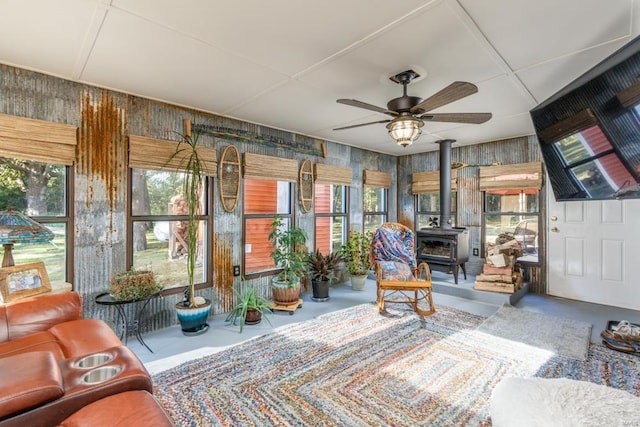 interior space featuring a wood stove, a ceiling fan, and concrete flooring