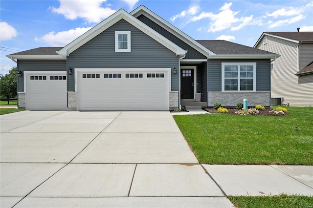 craftsman house featuring concrete driveway, stone siding, an attached garage, central air condition unit, and a front yard