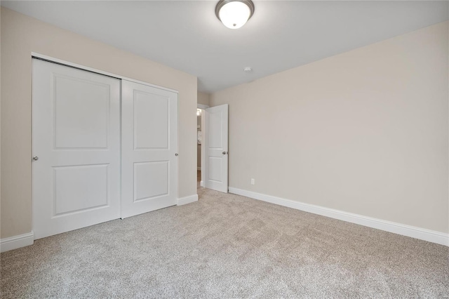 unfurnished bedroom with light carpet and a closet