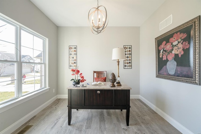 home office featuring an inviting chandelier and light hardwood / wood-style flooring