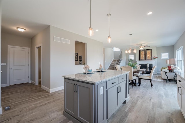 kitchen with ceiling fan, plenty of natural light, light hardwood / wood-style floors, and a center island