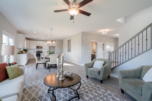 living room with ceiling fan with notable chandelier and wood-type flooring