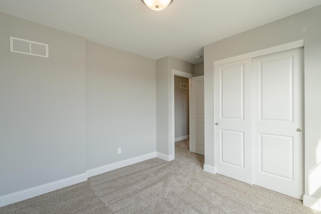 unfurnished bedroom with a closet and light carpet