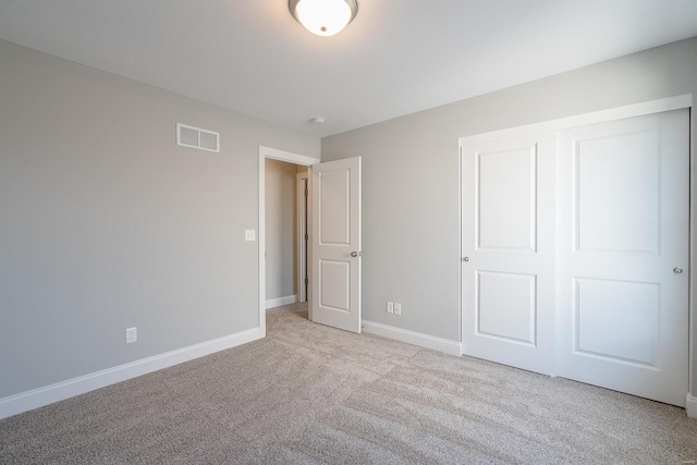 unfurnished bedroom featuring light colored carpet and a closet