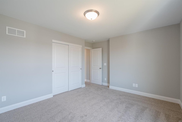 unfurnished bedroom featuring light carpet and a closet