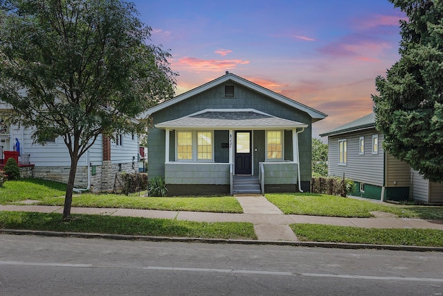 bungalow-style home featuring covered porch and a yard