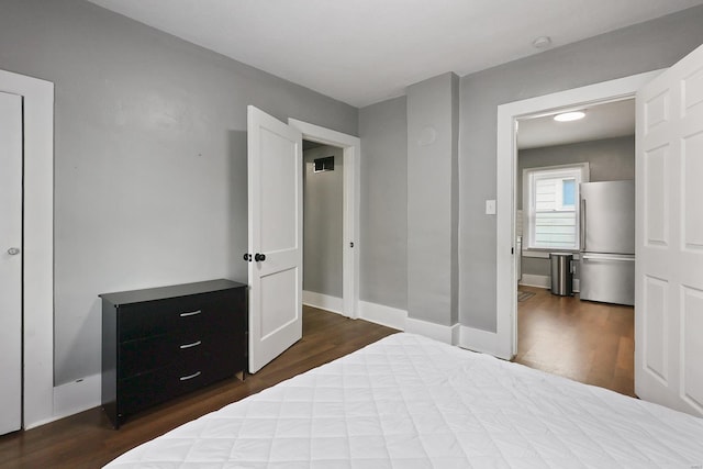 bedroom with hardwood / wood-style flooring and stainless steel fridge