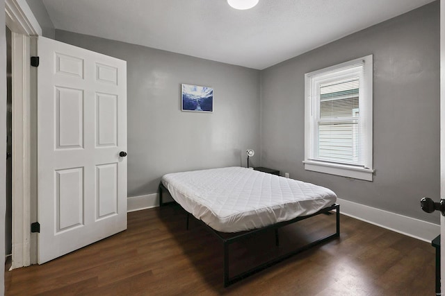 bedroom with dark hardwood / wood-style flooring