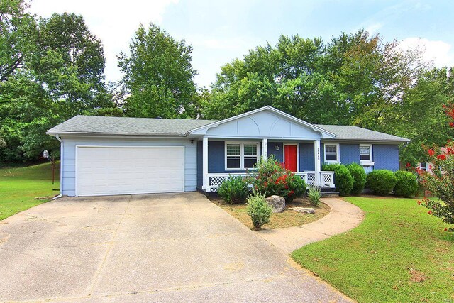 single story home featuring a front yard, covered porch, and a garage