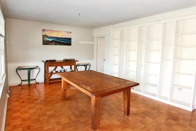 interior space with a textured ceiling, parquet floors, and built in shelves