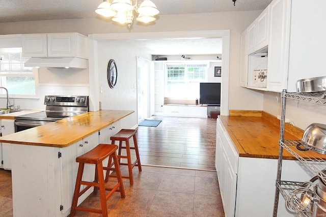 kitchen featuring light wood-type flooring, custom range hood, butcher block counters, and white cabinetry