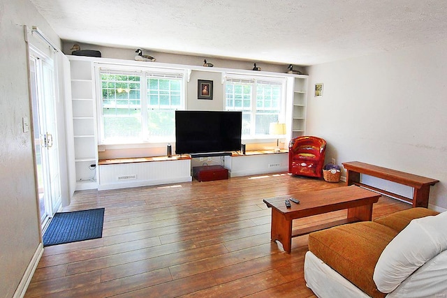 living room with a textured ceiling, plenty of natural light, and hardwood / wood-style floors