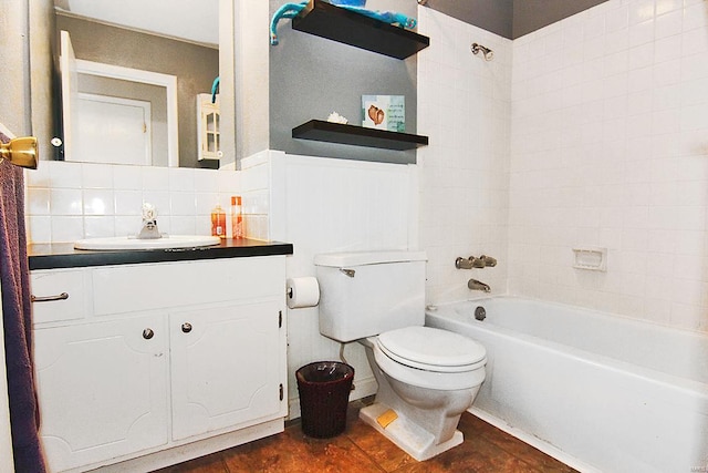 full bathroom featuring tile walls, tiled shower / bath, toilet, vanity, and tasteful backsplash