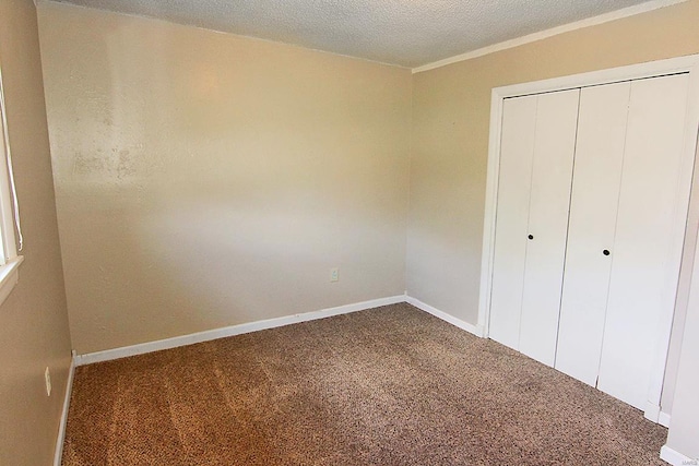 unfurnished bedroom featuring a textured ceiling, carpet floors, and a closet