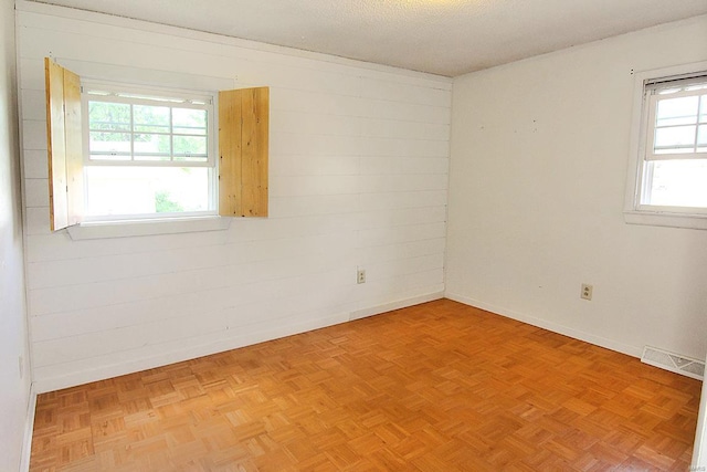 spare room featuring a textured ceiling and light parquet flooring