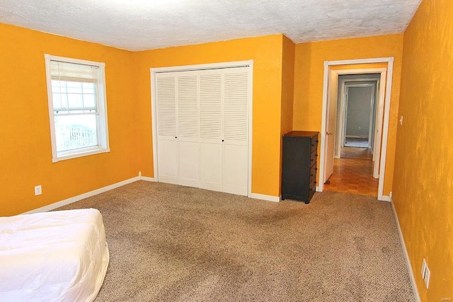 unfurnished bedroom with a textured ceiling, a closet, and carpet