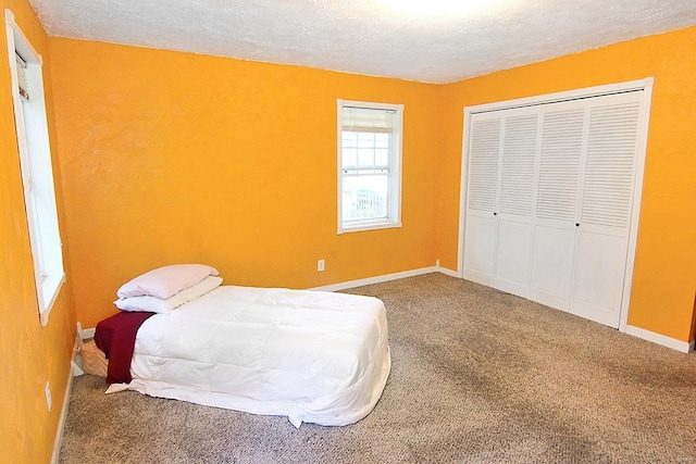 carpeted bedroom with a textured ceiling and a closet