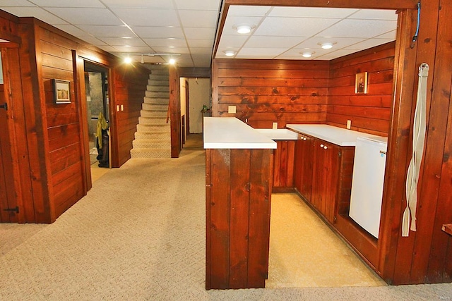 interior space with light carpet, a paneled ceiling, and a center island