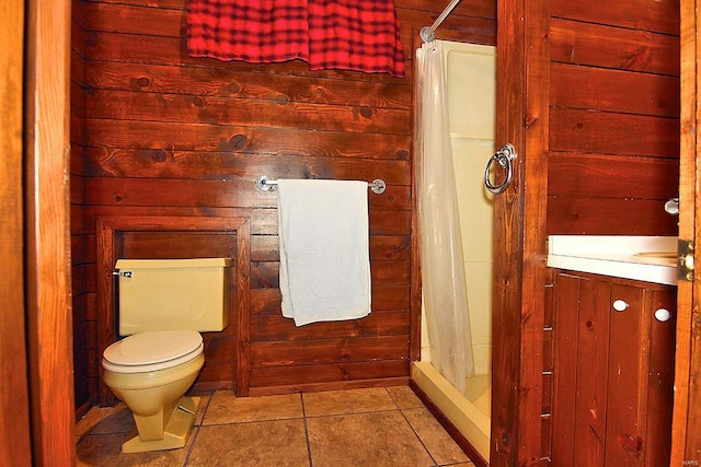 bathroom featuring toilet, wooden walls, tile patterned floors, a shower with shower curtain, and vanity