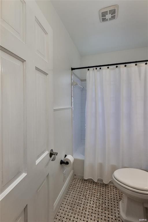 bathroom with toilet, tile patterned flooring, and shower / bath combination with curtain