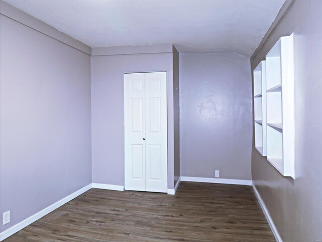 unfurnished bedroom with dark wood-type flooring and a closet