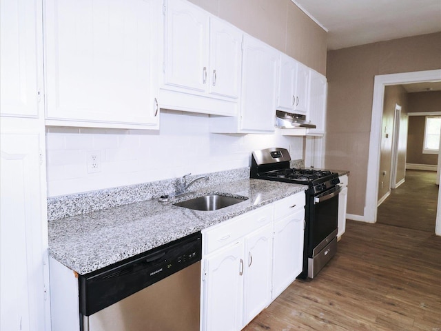 kitchen with stainless steel appliances, white cabinetry, sink, light stone counters, and hardwood / wood-style flooring