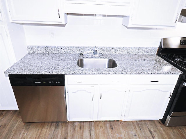 kitchen with sink, hardwood / wood-style flooring, light stone countertops, stainless steel appliances, and white cabinets