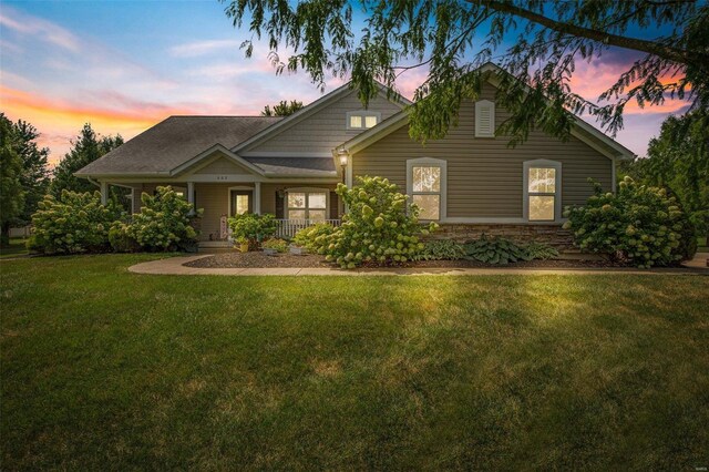 view of front of property featuring covered porch and a yard