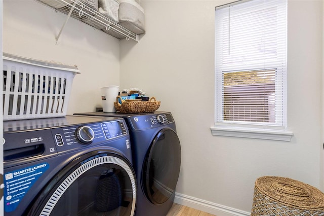 washroom featuring laundry area, baseboards, washer and clothes dryer, and light wood-style floors