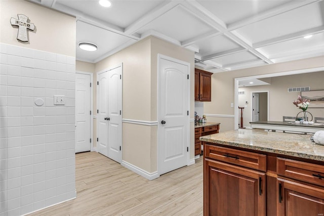 kitchen with visible vents, light wood-style flooring, light stone countertops, coffered ceiling, and baseboards