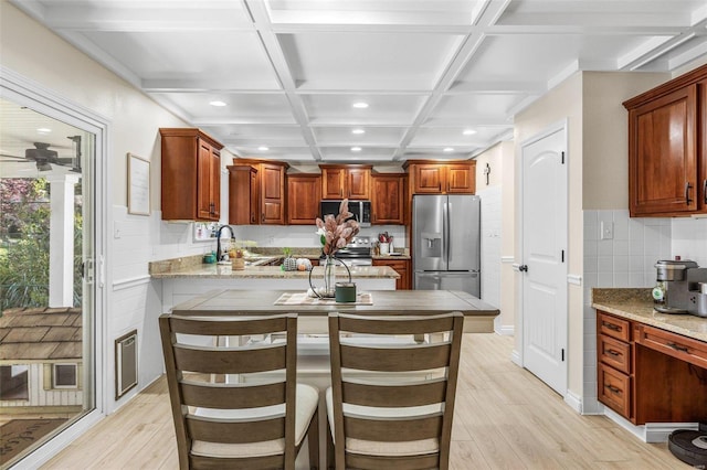 kitchen featuring light stone countertops, coffered ceiling, a kitchen bar, and stainless steel appliances